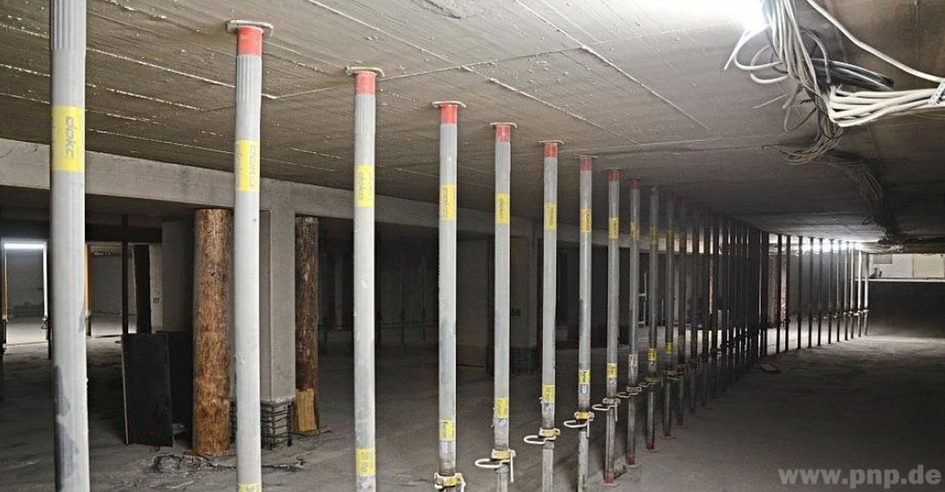 Aufgereihte Stahlstützen stabilisieren die Tiefgarage während der Arbeiten. Noch besser tragen die Baumstämme, die vor allem jeweils auf beiden Seiten von Säulen eingespreizt wurden. −Foto: Schreiber Aufgereihte Stahlstützen stabilisieren die Tiefgarage während der Arbeiten. Noch besser tragen die Baumstämme, die vor allem jeweils auf beiden Seiten von Säulen eingespreizt wurden. −Foto: Schreiber